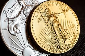 A high definition photograph of a U.S. silver dollar behind a U.S. gold dollar.