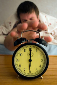 man walking up getting ready to turn off an alarm clock.