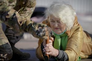 A Ukraine woman with gray hair aiming an AK47 submachine gun.