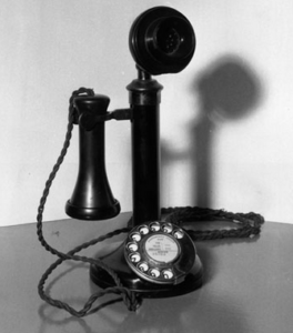 A black and white photo of a very old phone.  It is a phone that you hold a cone like device to your ear.  ANYONE can afford silver